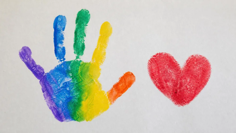 Toddler's two red thumbprints pressed into a heart beside a painted handprint.