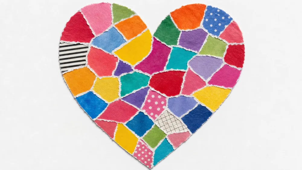 Heart outline filled with torn scraps of colorful paper in a mosaic.