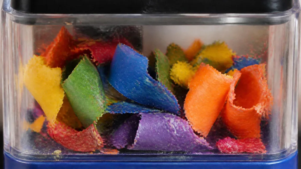 Close-up of soft wax crayon shavings clumped inside a sharpener's clear shavings box.