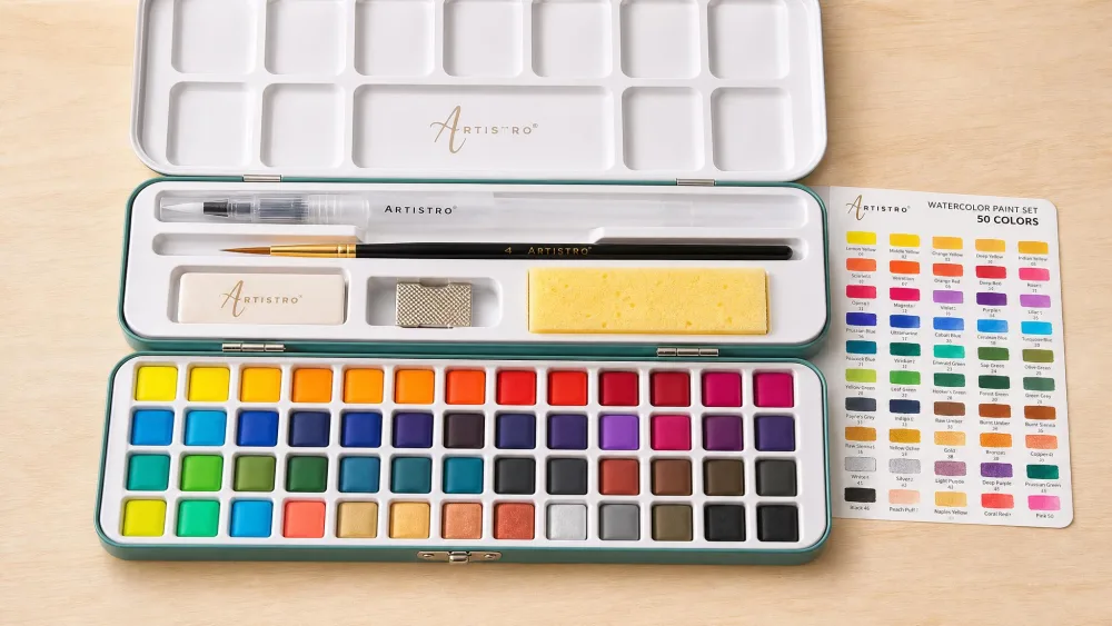 The ARTISTRO 50-color metal tin open, showing its built-in mixing tray, refillable water brush, and nylon brush.