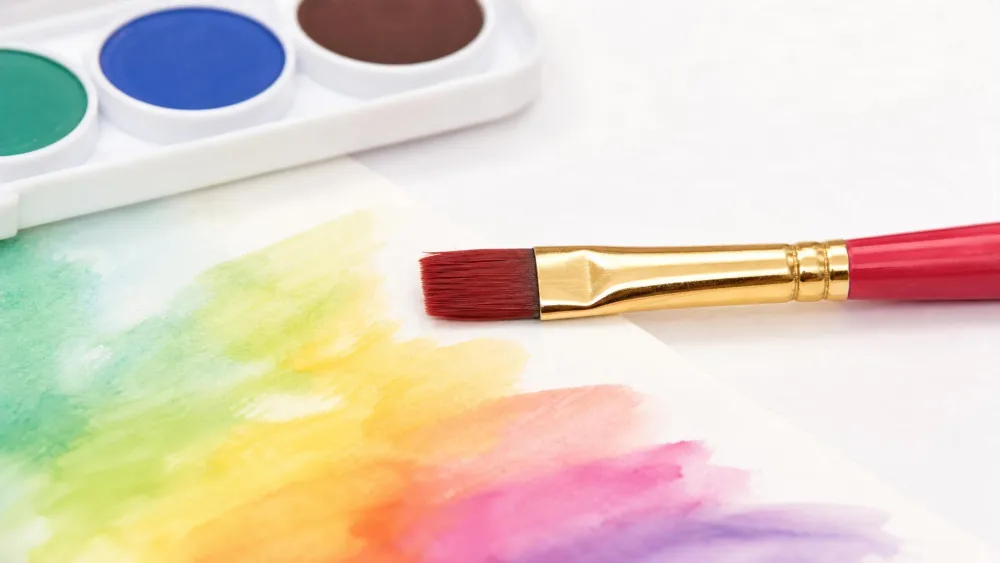 Close-up of the Faber-Castell watercolor set's included brush, its bristle tip intact and unfrayed, beside painted paper.