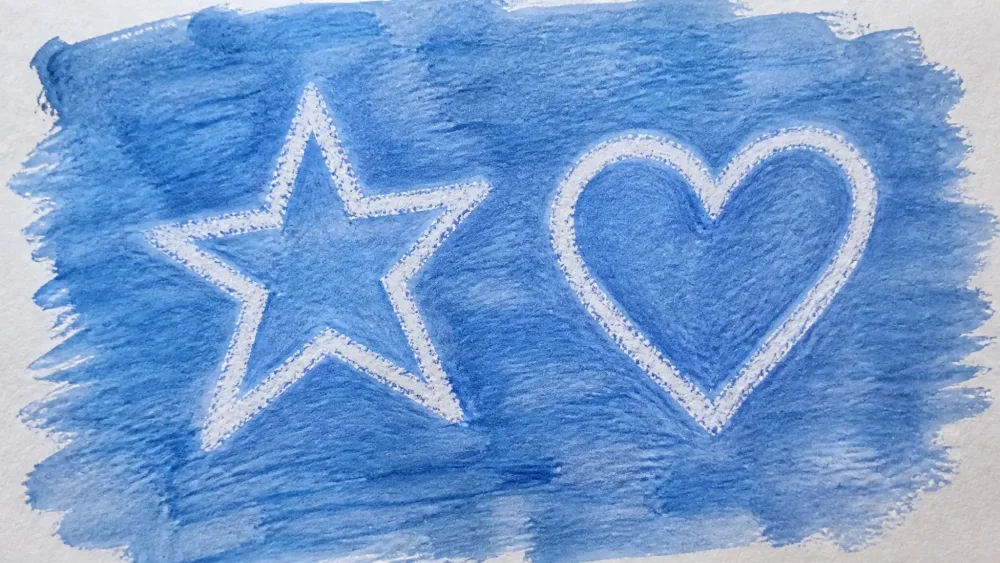 A blue wash brushed over white paper revealing a hidden white-crayon drawing of a star and a heart that resist the paint.