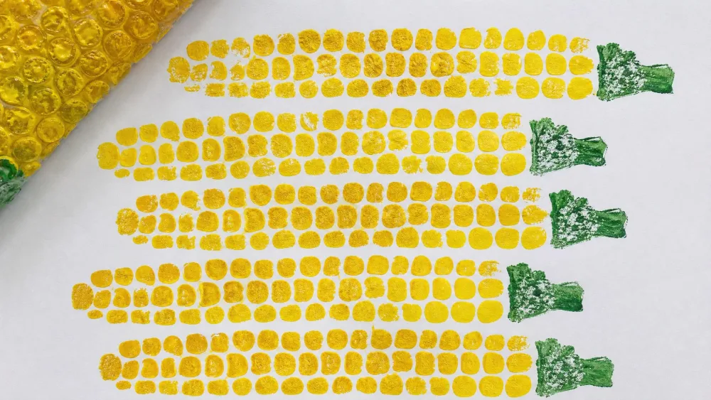 Rows of corn kernels stamped by pressing paint-covered bubble wrap onto paper.