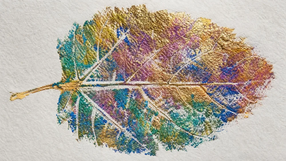 A shiny textured leaf print made by pressing paper onto watercolor-painted foil.