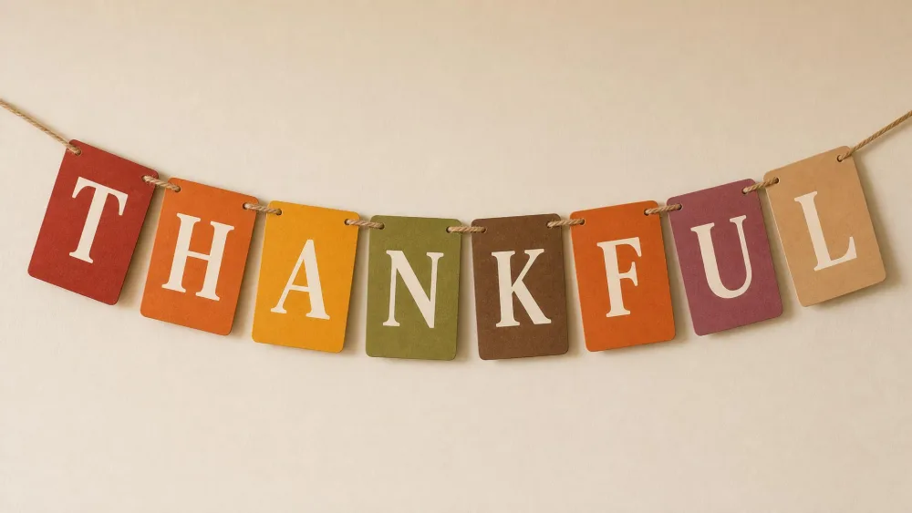 Printed and colored letter tiles spelling THANKFUL strung into a banner on a wall.