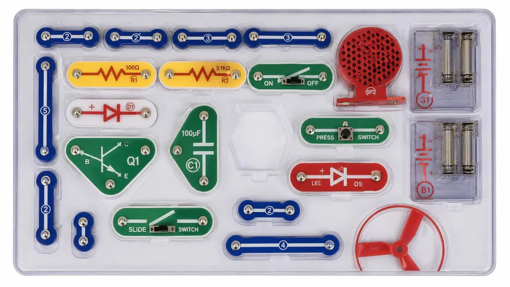 An open Snap Circuits storage tray photographed from above, most moulded slots filled with colour-coded snap parts and one empty slot clearly visible near the centre.