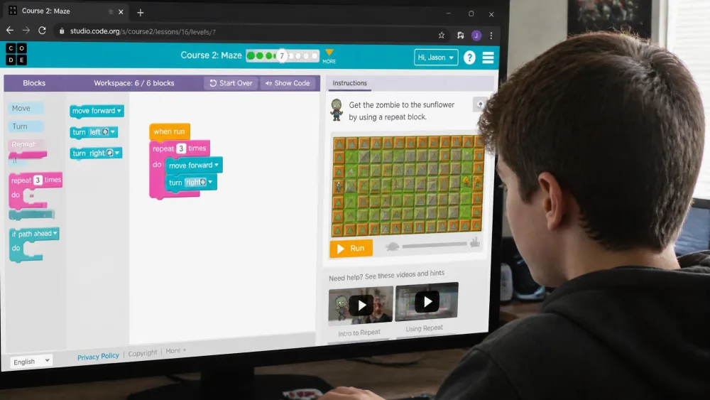 A thirteen-year-old working a Code.org course puzzle in a browser, block workspace on the left.