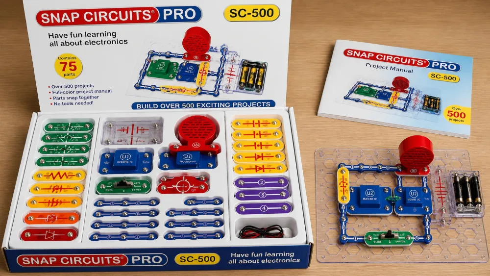 The open Snap Circuits Pro SC-500 box showing 75 colour-coded parts sorted in the moulded storage tray, with a voice-recorder circuit built on the base grid beside it.
