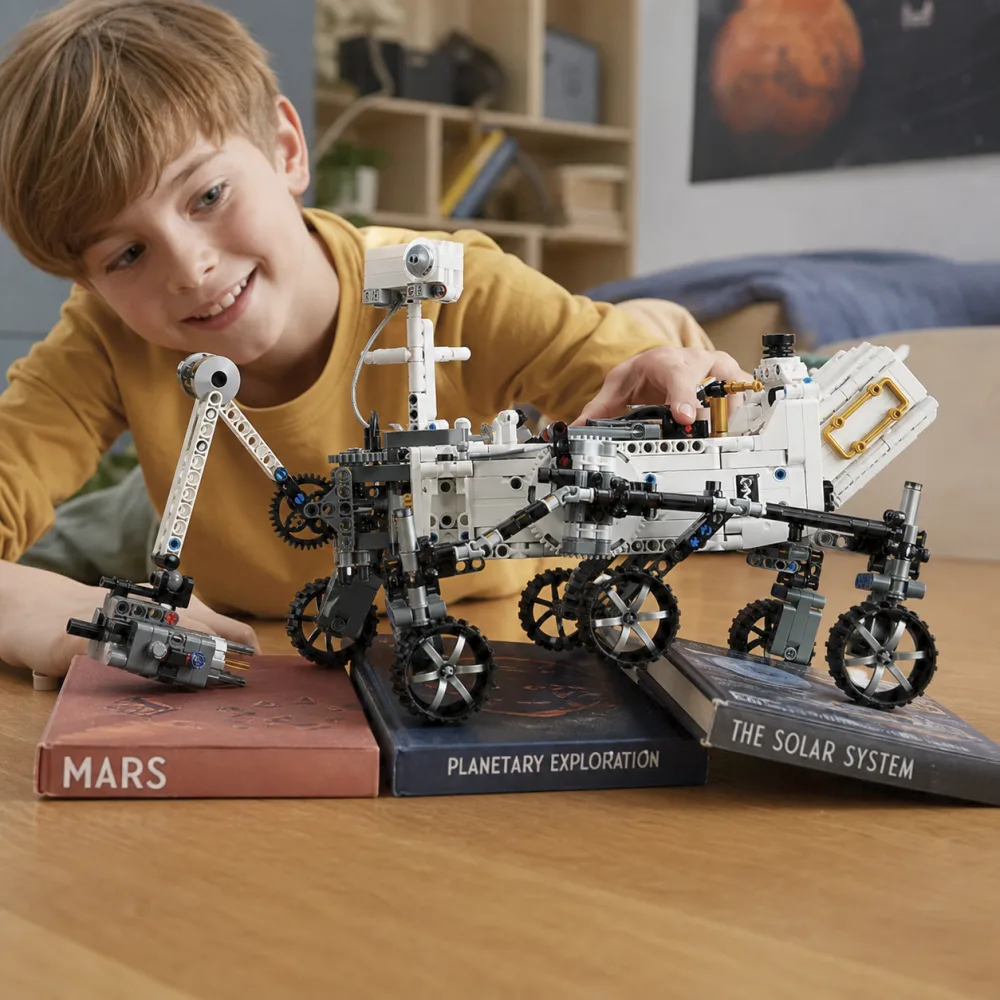 A child rolling the completed LEGO 42158 Mars Rover over a stack of books on the floor, showing the rocker-bogie suspension keeping all six wheels in contact with the uneven surface.
