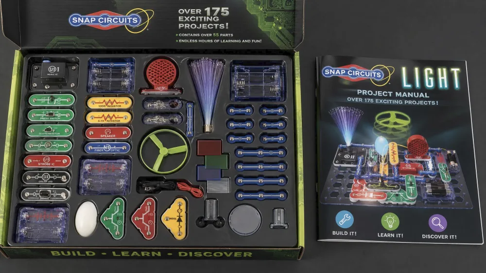 Open Snap Circuits LIGHT SCL-175 box showing color-coded parts beside the full-color project manual.