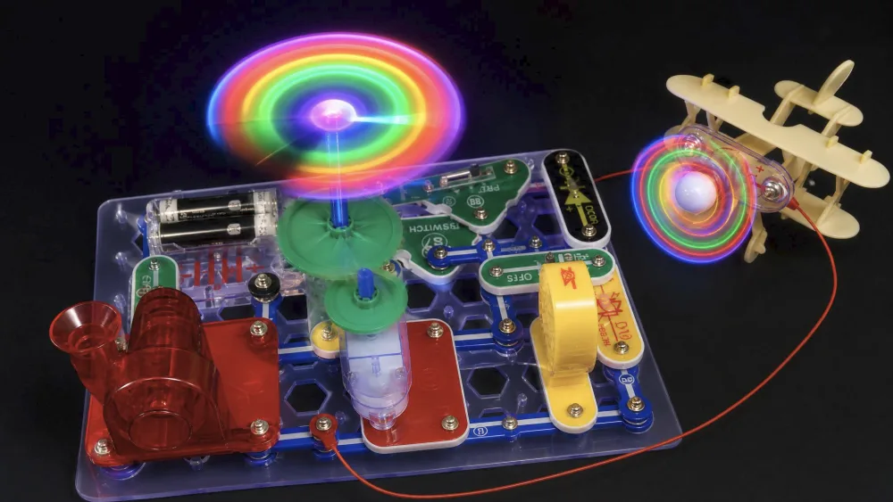 The assembled Snap Circuits Motion color-changing lighted fan mid-spin, the blades glowing as they turn on the green plastic Snap Circuits base.